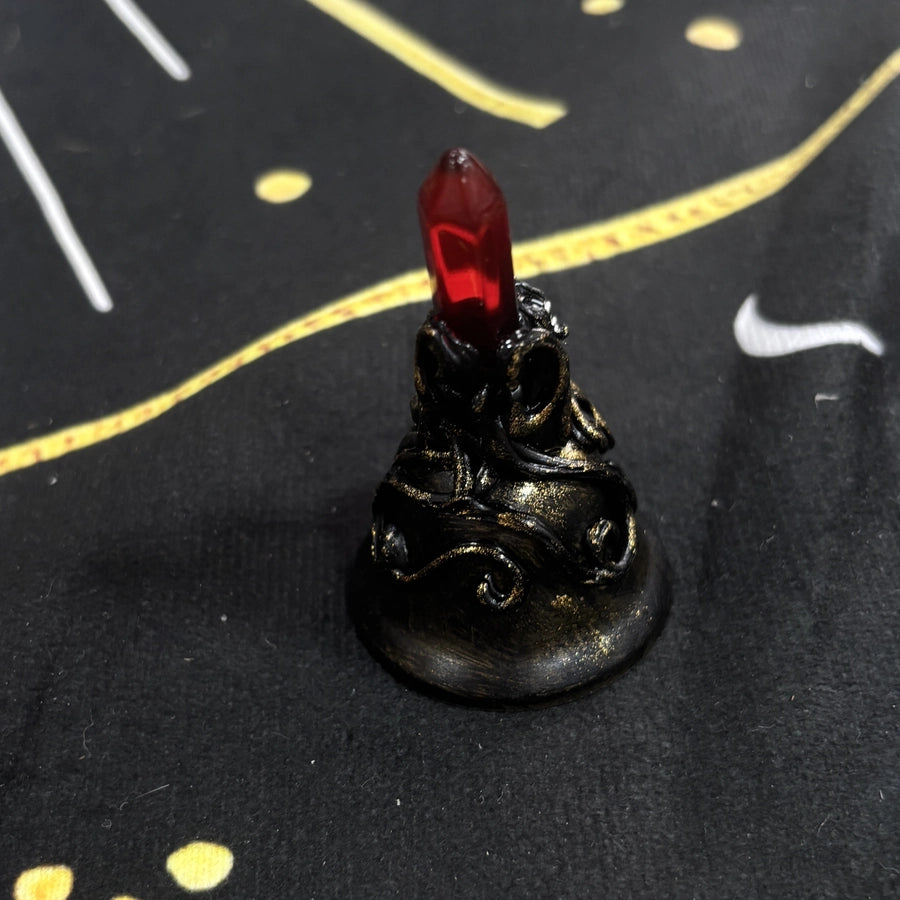 Back view of a handmade red crystal witch bell showing sculpted black and antique gold texture